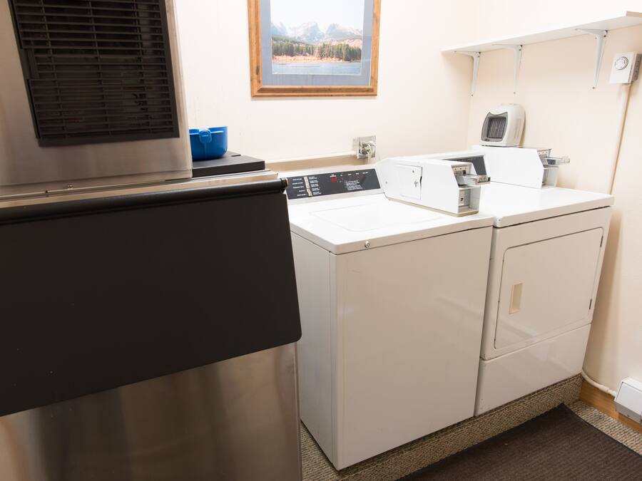 A laundry area with a stainless steel washer and dryer, a window with a mountain view, and a blue basin on the counter.