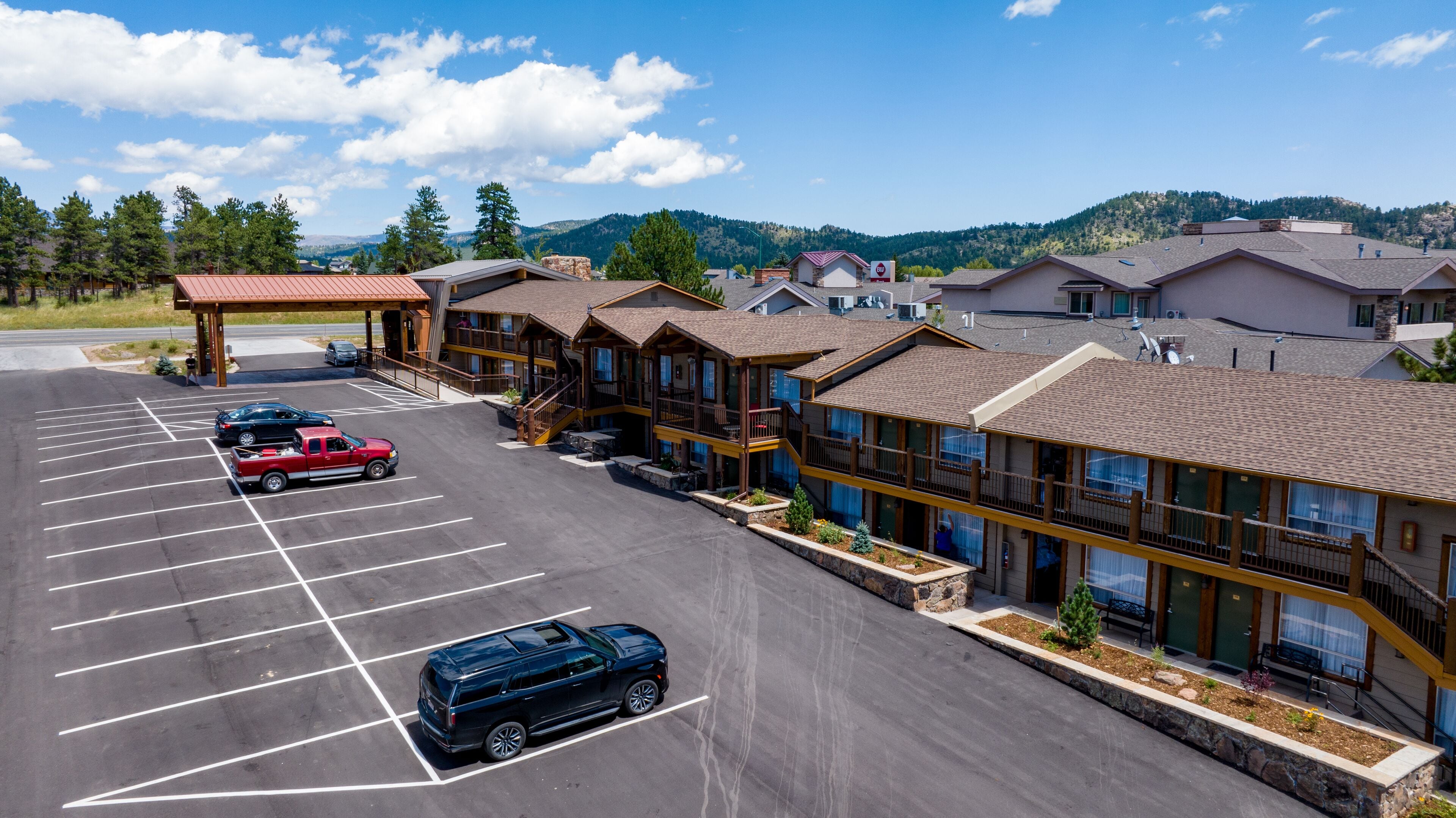 A hotel with a parking lot, multiple buildings, and a mountainous backdrop.