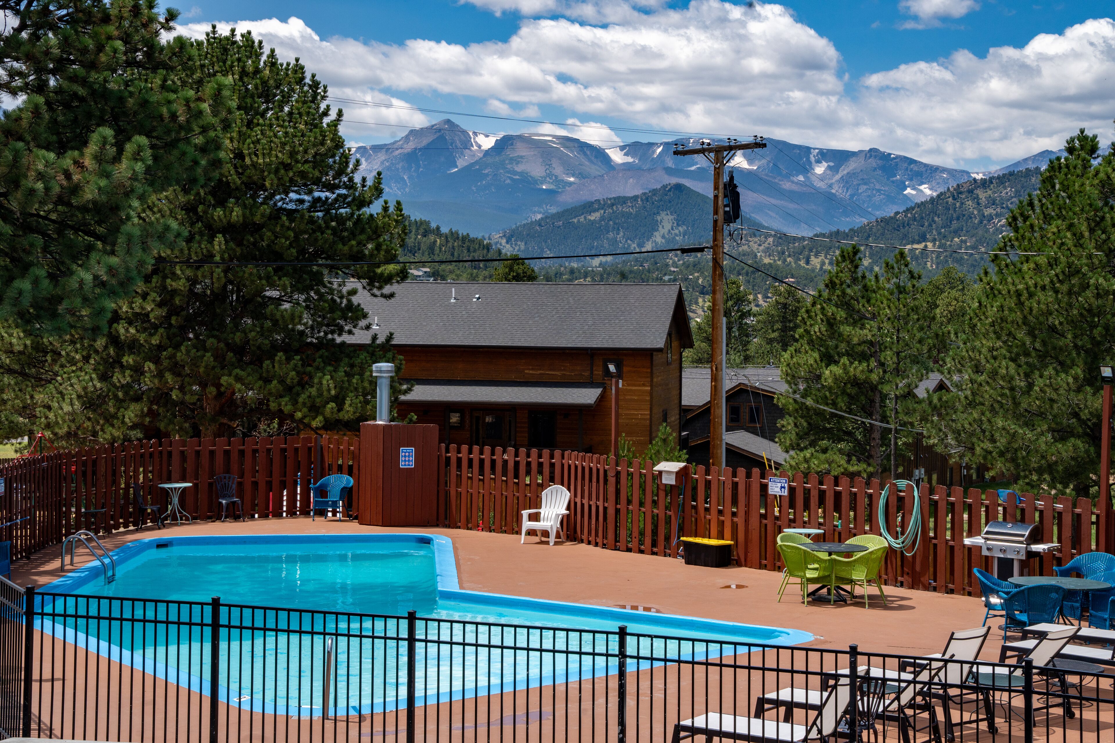 A swimming pool with a wooden deck, outdoor furniture, and a view of mountains in the background.