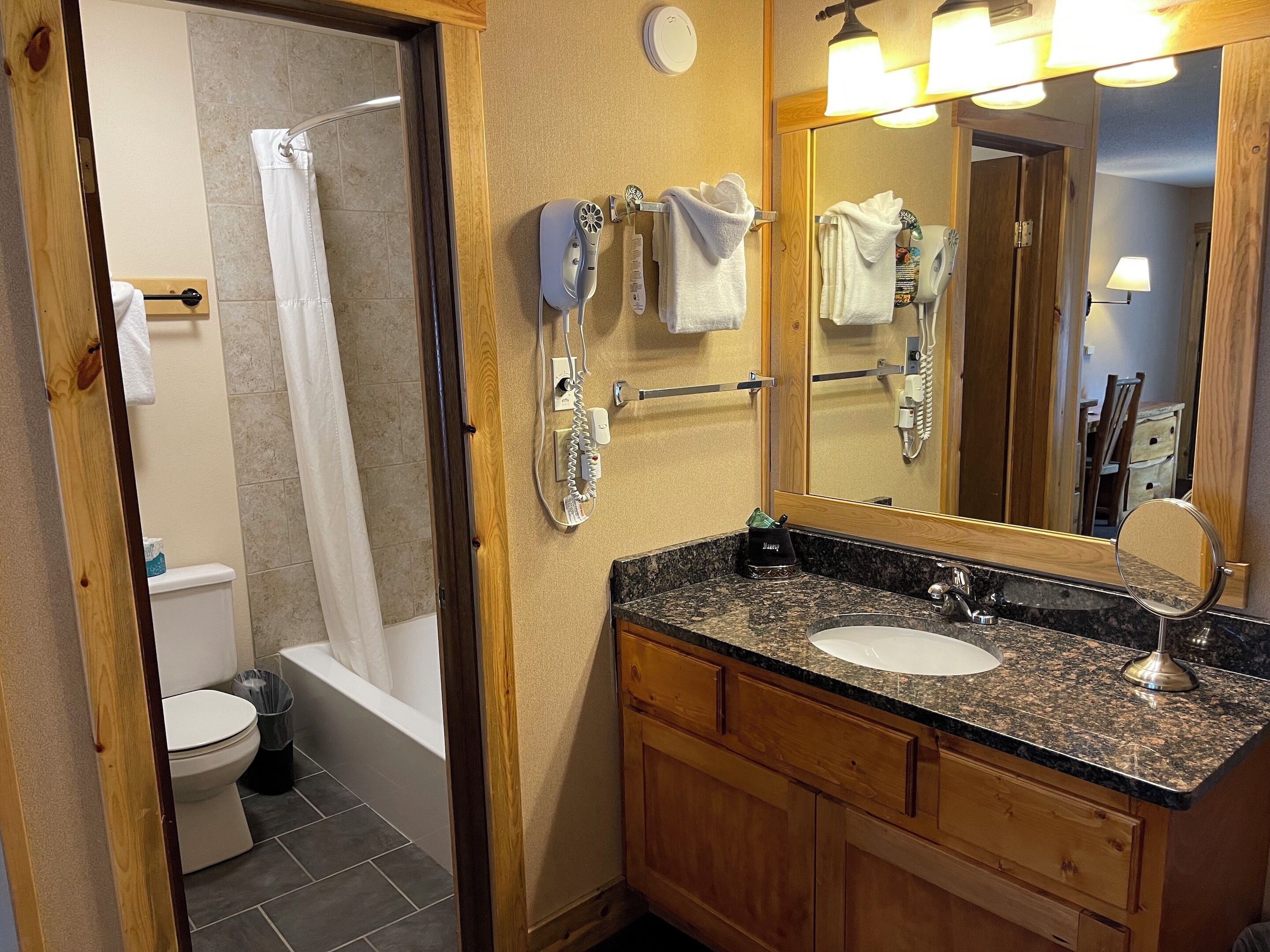 A bathroom with a shower, toilet, sink, and towel rack.