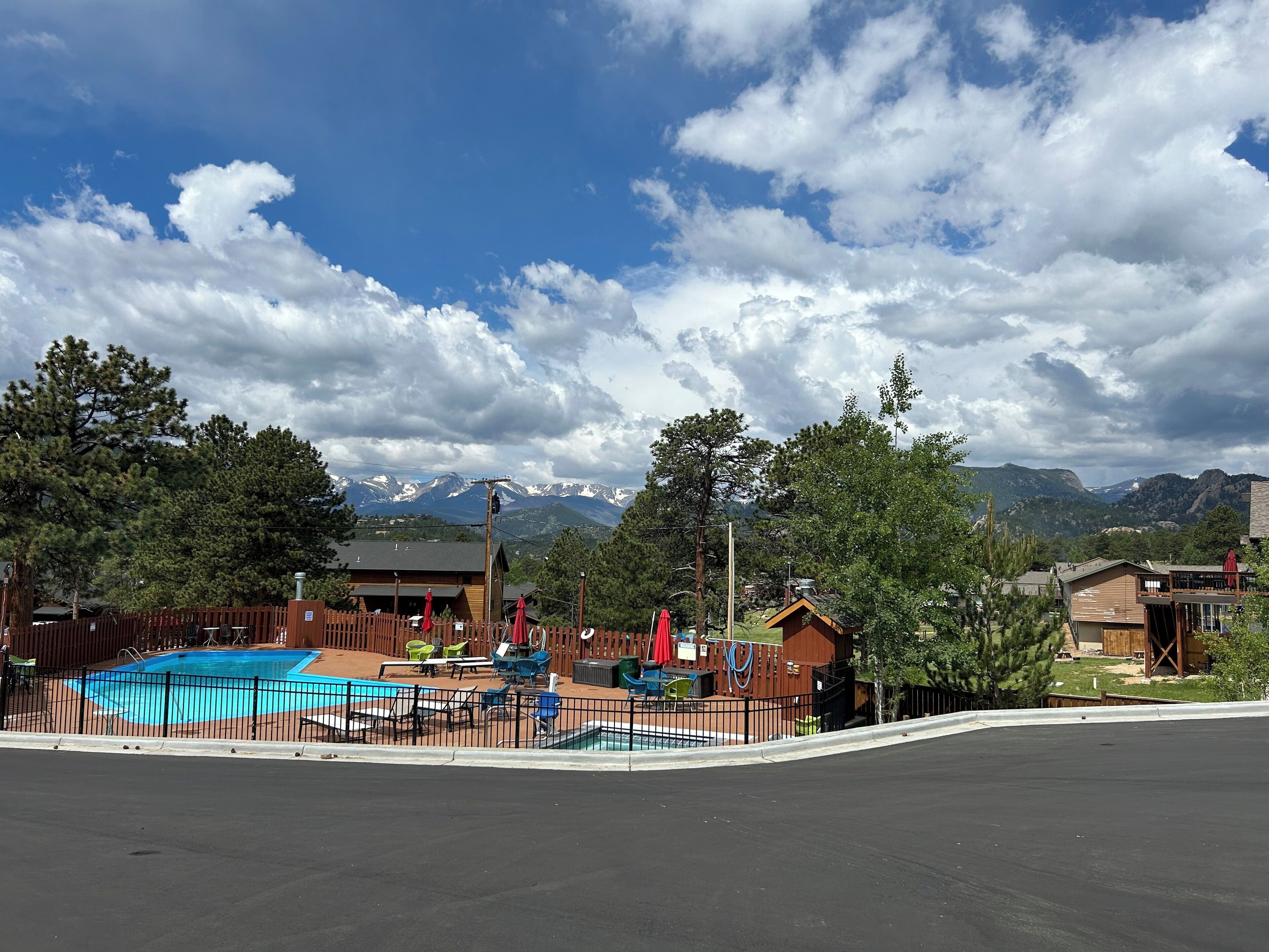 A pool area with a fenced deck, outdoor seating, and a mountain backdrop.