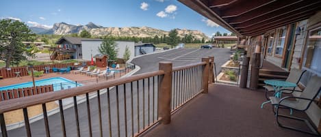 A balcony with a view of a pool and mountains.