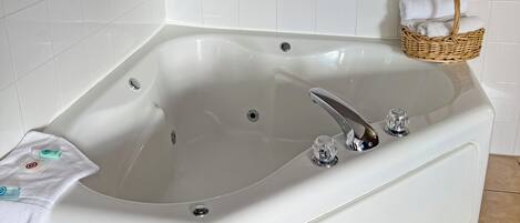 A white bathtub with a chrome faucet, a small glass bottle, and a white towel on the side.