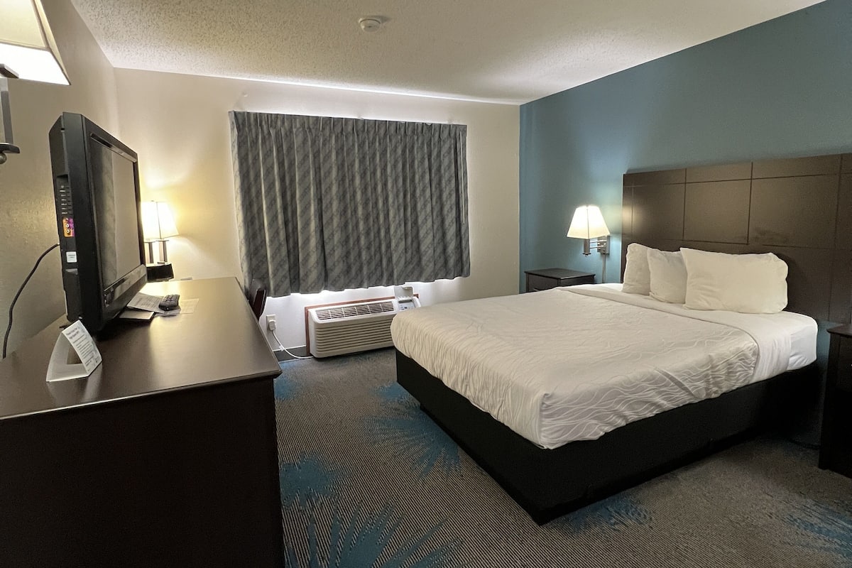 A hotel room with a bed, desk, and a television.