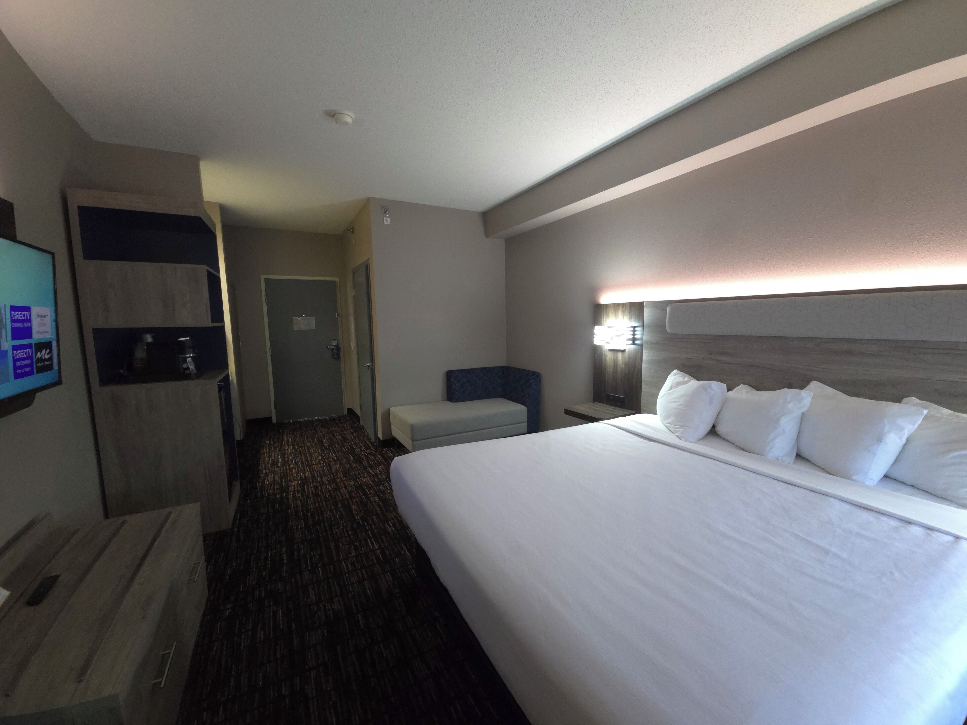 Una habitación de hotel con una cama grande, un escritorio, una silla, un televisor y una puerta.