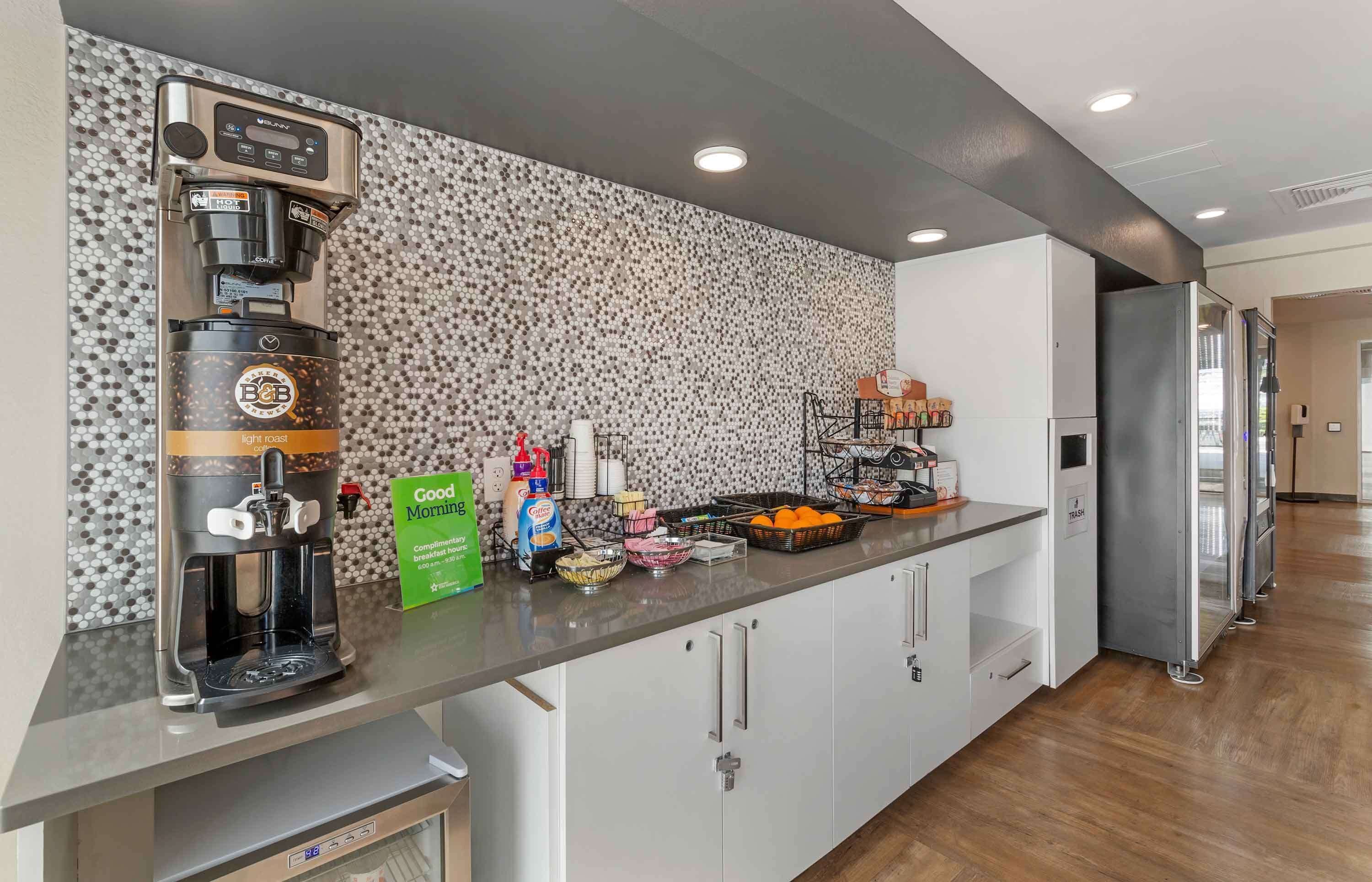 Una cocina moderna con cafetera, barra de desayuno y diferentes alimentos.