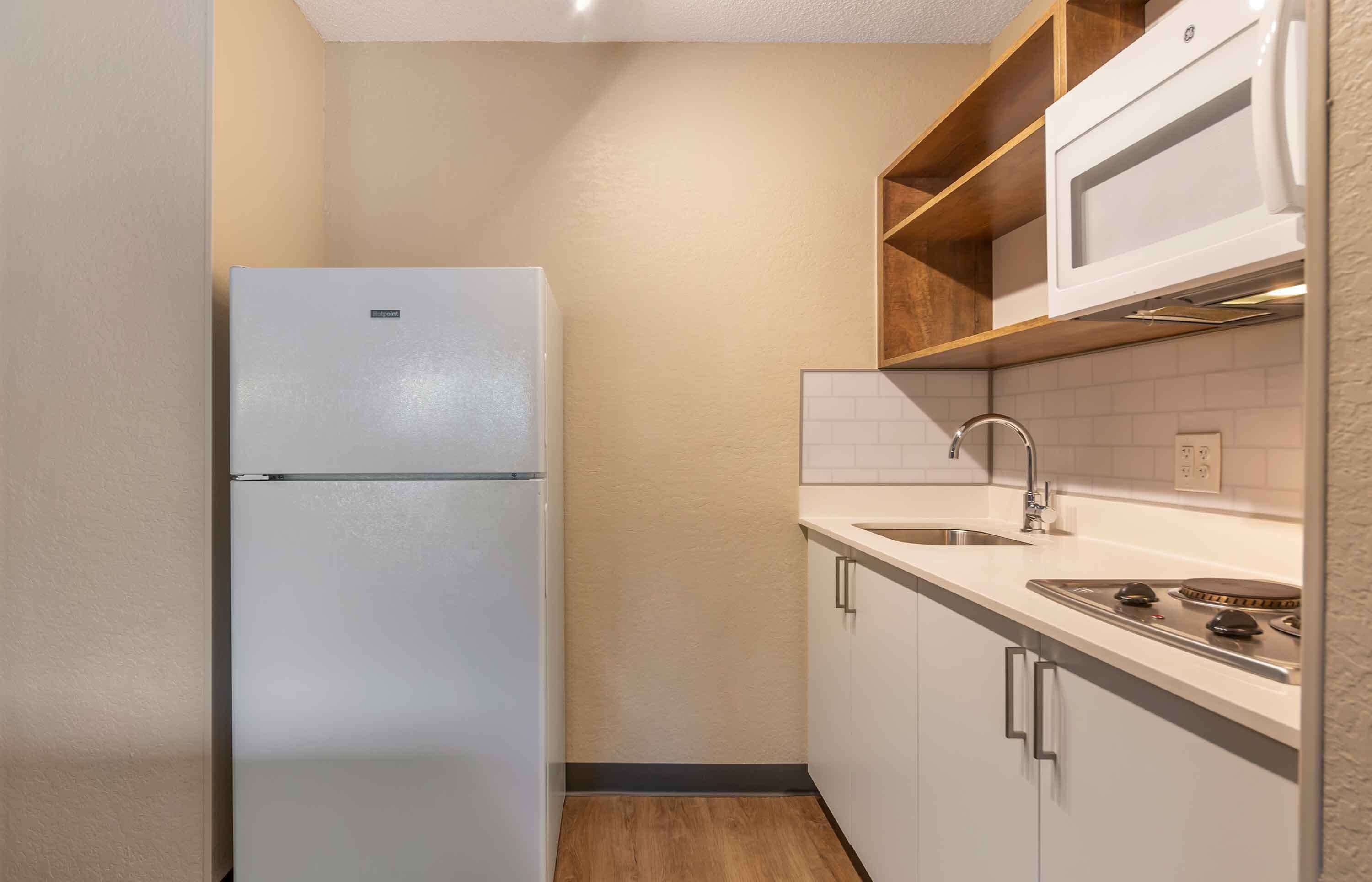 Una cocina compacta con un refrigerador blanco, un fregadero y una estufa.