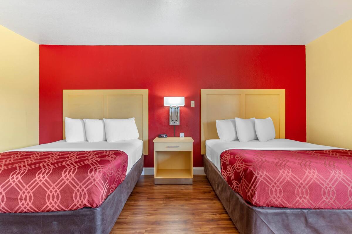Une chambre d’hôtel avec deux lits, une table de chevet et une lampe fixée au mur.