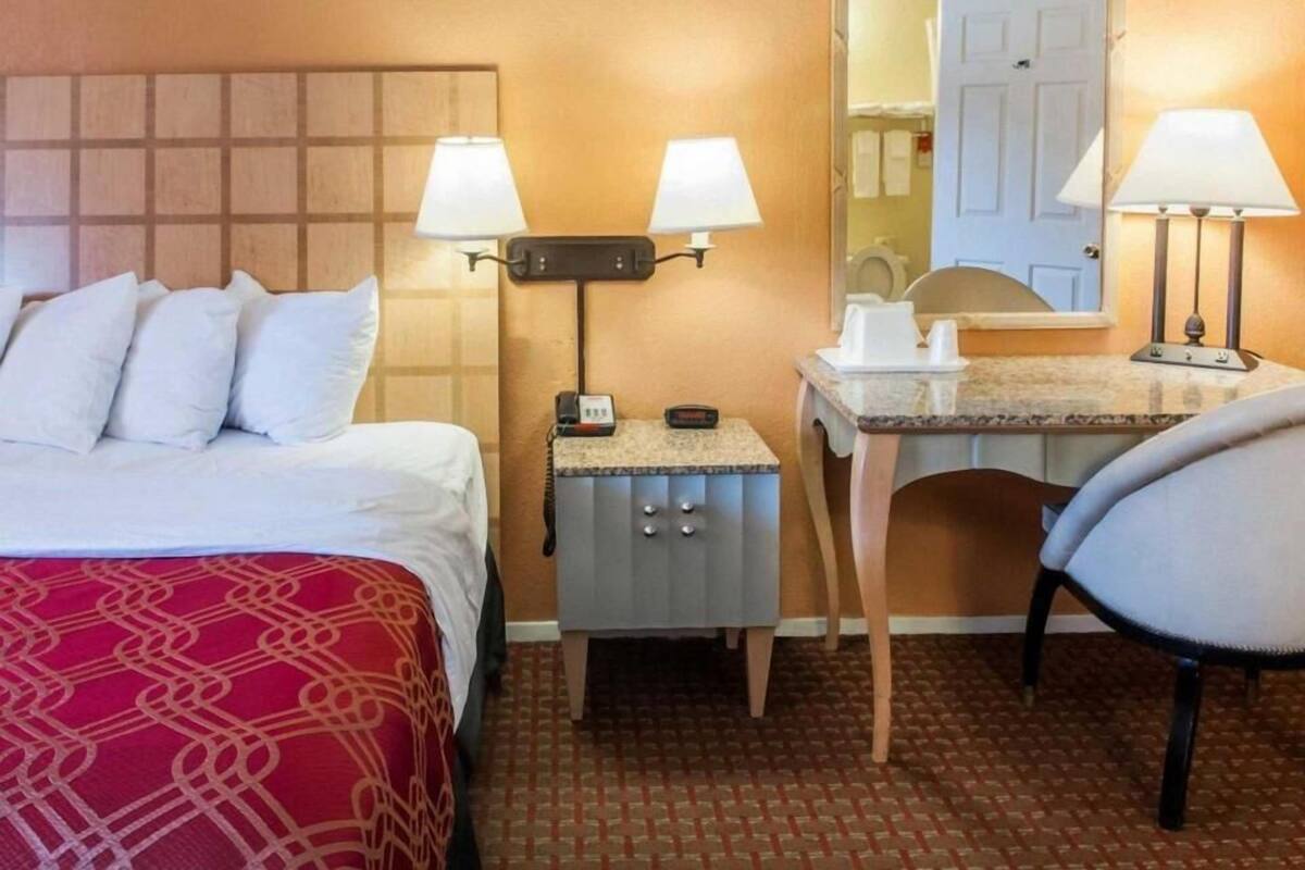 Une chambre d’hôtel équipée d’un lit, d’un bureau, d’une chaise, d’un téléphone et d’un miroir.