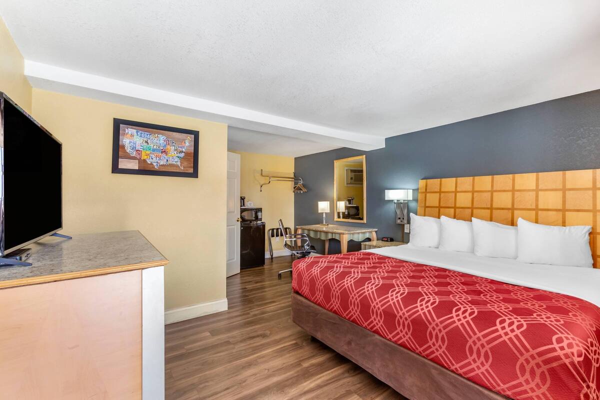 Une chambre d’hôtel avec un lit, un bureau, une télévision et une carte accrochée au mur.