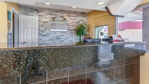 A reception area with a stone wall, a sign reading "EconoLodge," and a reception desk with a plant. - Econo Lodge Clovis (Clovis)