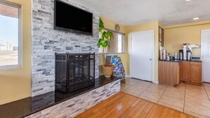 A modern kitchen with a stone backsplash, a flat-screen TV, a potted plant, and a wooden cabinet. - Econo Lodge Clovis (Clovis)