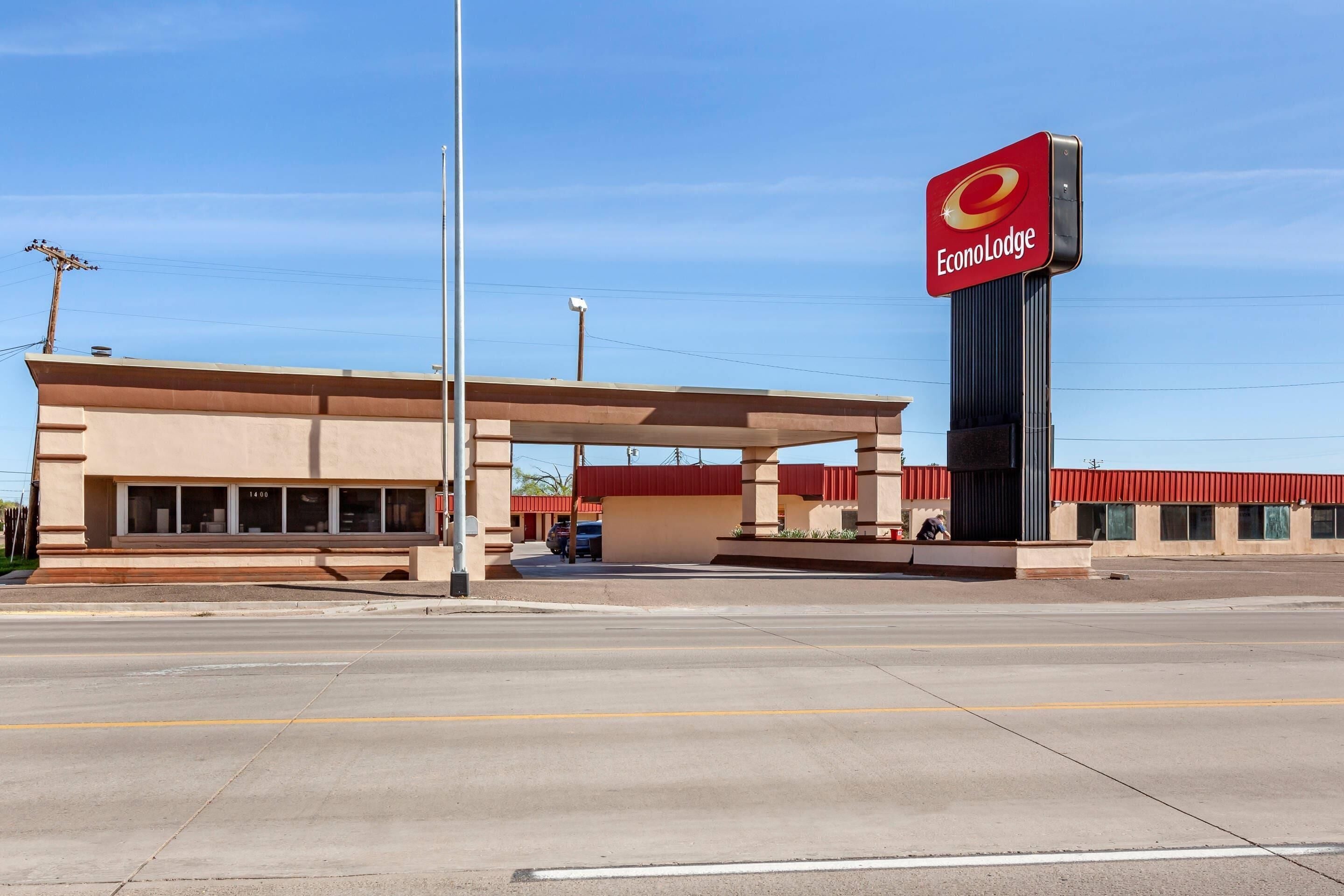 A EconoLodge building with a red sign, a covered parking area, and a clear sky.