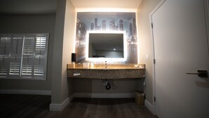 A bathroom with a granite countertop, a sink, and a mirror. - Mid City Inn and Suites (Pico Rivera)