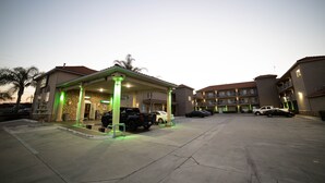 A parking area with a gas station and a building with multiple balconies. - Mid City Inn and Suites (Pico Rivera)