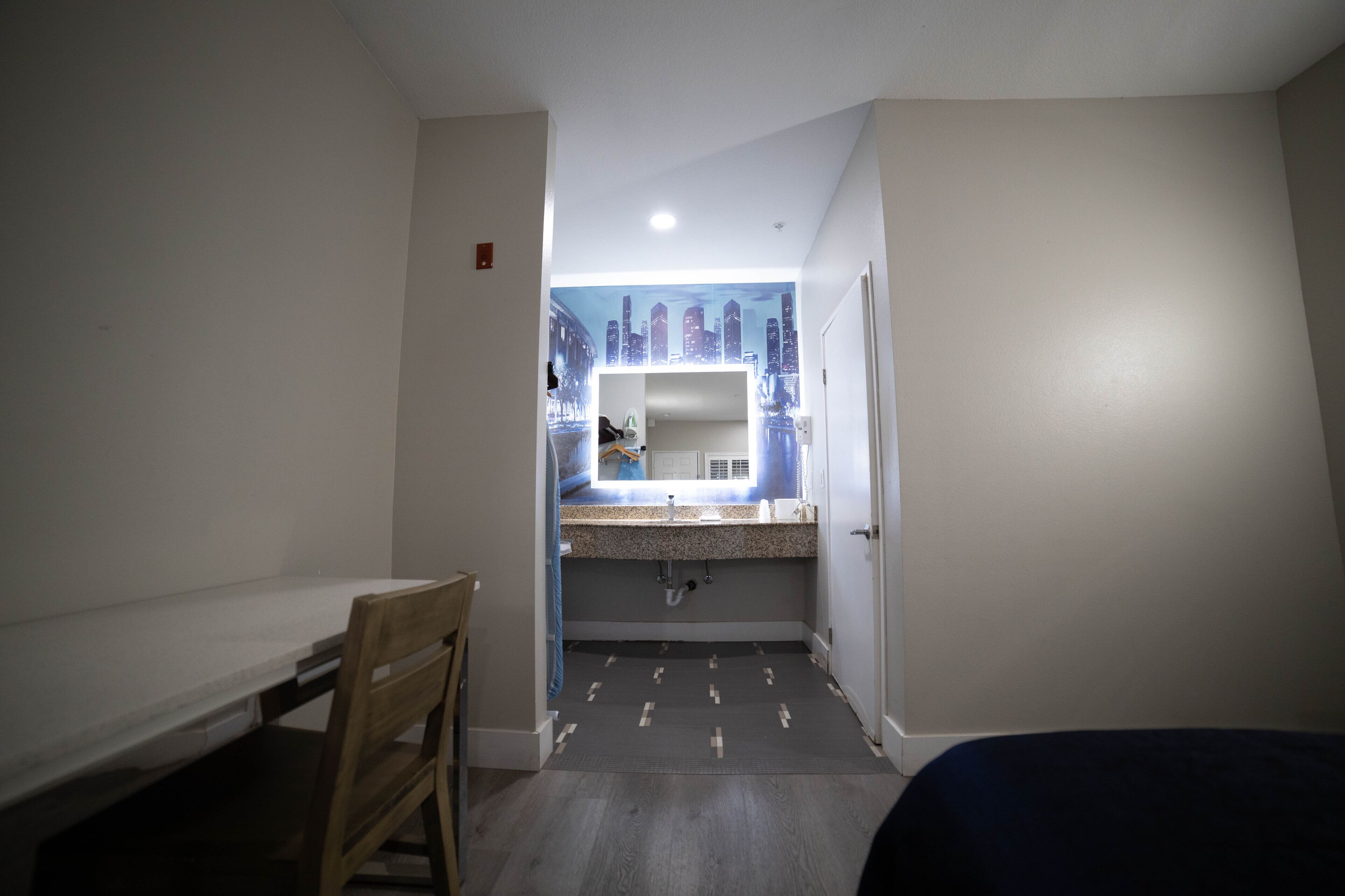 A narrow hallway leading to a bathroom with a mirror, sink, and towel rack.