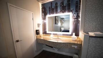 A bathroom with a granite countertop sink, a mirror above it, and a white door.