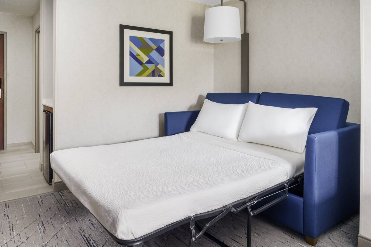 Een moderne kamer met een bed, een lijst met abstract schilderij en een vloerlamp.