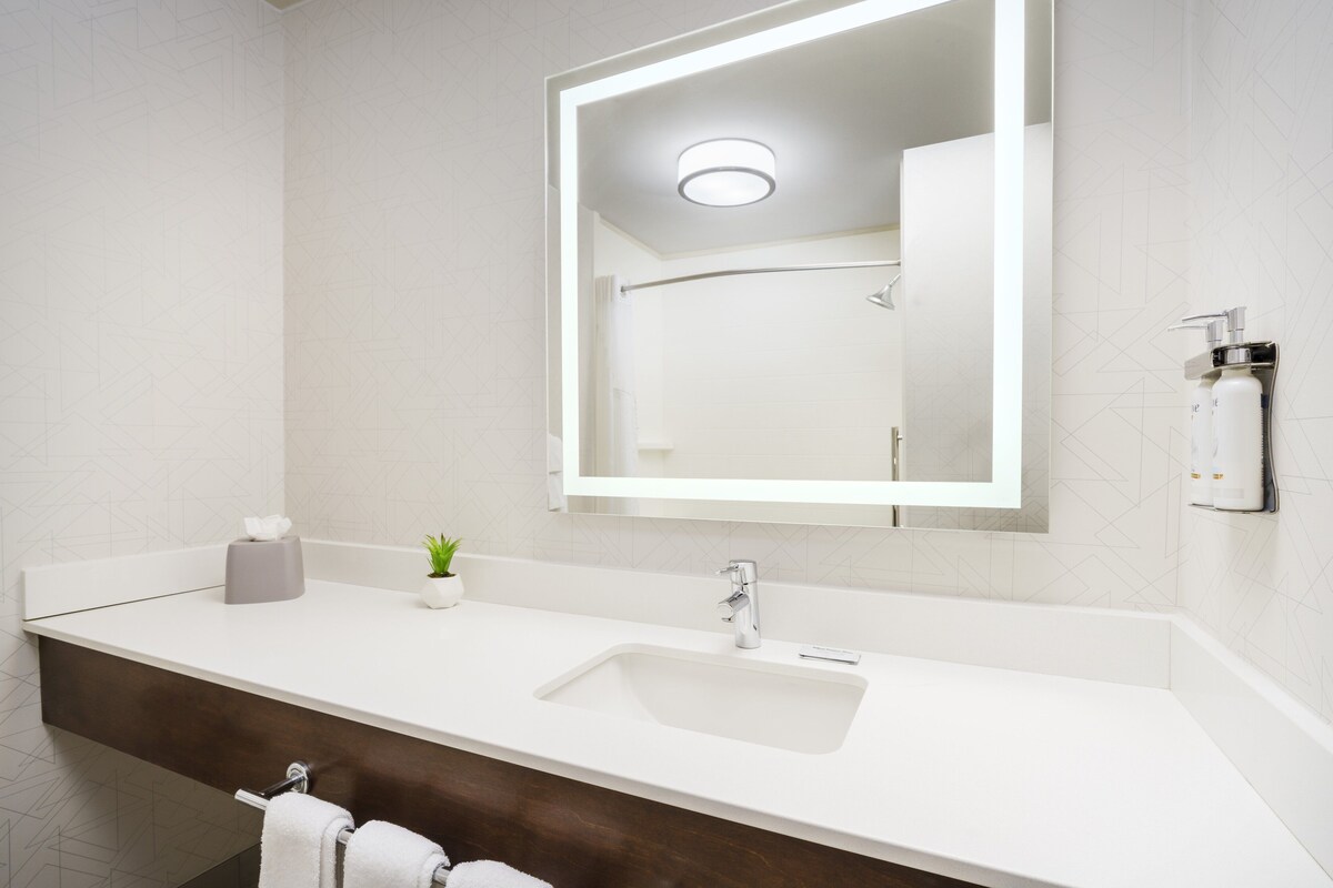 Un baño moderno con un lavamanos blanco, un espejo y un perchero para toallas.