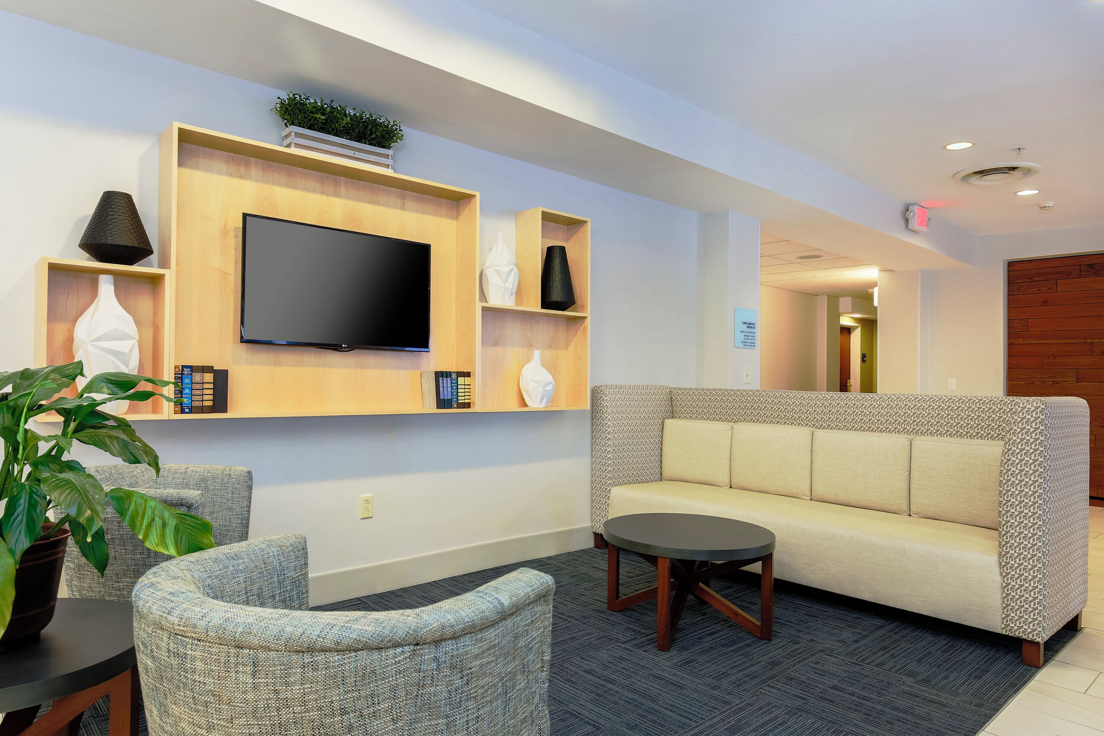 A modern lounge area with a flat-screen TV, a sofa, and a round coffee table.