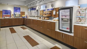 A bakery counter with various baked goods and a refrigerator stocked with beverages. - Holiday Inn Express Rochester NE- Irondequoit by IHG (Rochester)