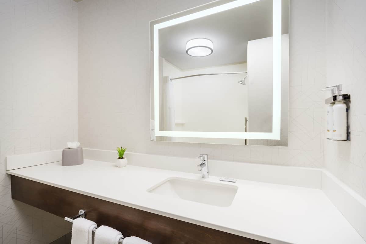 Een moderne badkamer met een wit wastafelmeubel, een spiegel en een handdoekrek.