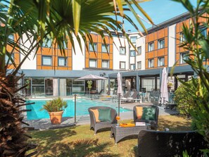 Ein Hotel mit Schwimmbad, Außenbereich und einer modernen Fassade.