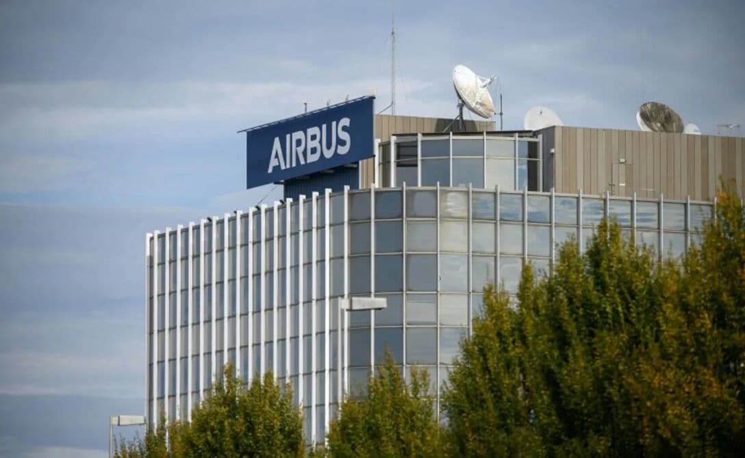 A modern building with a prominent 'AIRBUS' sign, large windows, and satellite dishes on the roof.