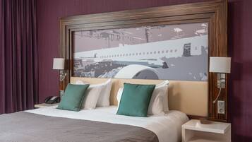 Habitación de hotel con una cama, una mesita de noche, un teléfono y una lámpara de pared.