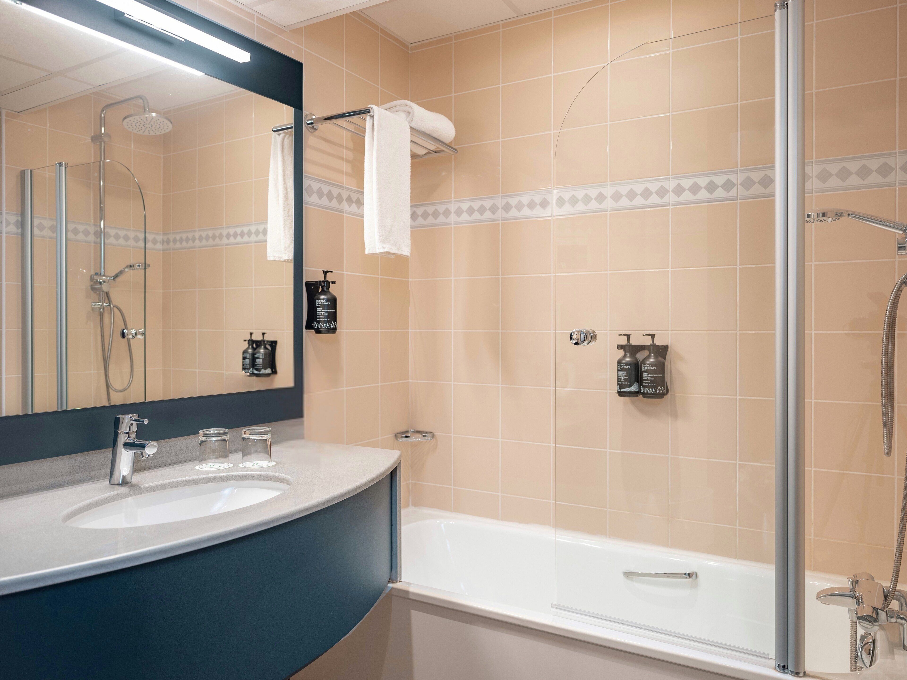 A bathroom with a bathtub, a shower, a sink, and a mirror.