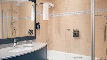 A bathroom with a bathtub, a shower, a sink, and a mirror.