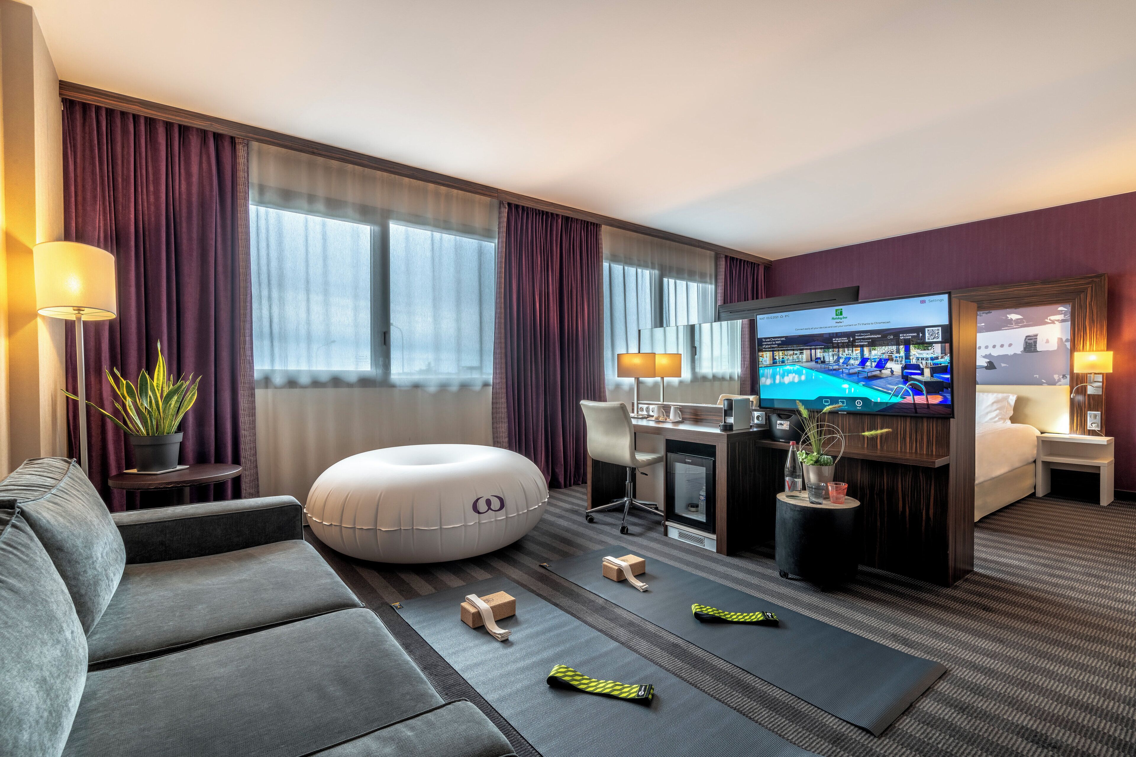 Een hotelkamer met een bank, een bureau met een computer, een televisie en een bed.
