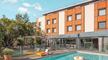 Relax by the pool surrounded by lush greenery and comfortable lounge chairs.