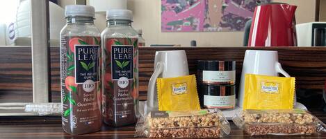 A hotel reception area with a wooden counter displaying various products including bottles of Pure Leaf tea, a coffee maker, and packaged snacks.