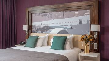 Ein Hotelzimmer mit einem großen Bett, zwei Nachttischlampen, einem Nachttisch mit Telefon und einem gerahmten Kunstwerk über dem Bett.
