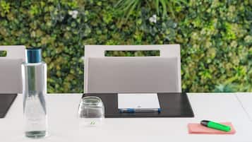 A conference table with a water bottle, a glass, a notepad, and a pen.