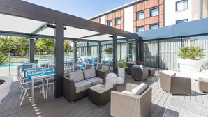 An outdoor patio area with seating, a pool, and a covered section. - Holiday Inn Toulouse Airport by IHG (Blagnac)