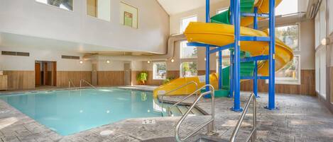 An indoor swimming pool with a water slide, a hot tub, and a staircase.