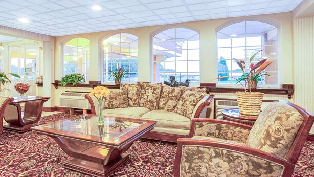 A spacious lobby with a large sofa, a coffee table, and a patterned carpet. There are large windows with views of the city and decorative plants. - Knights Inn Mount Laurel (Mount Laurel)