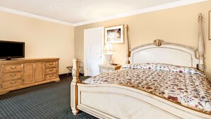 A hotel room with a large bed, a dresser, a television, and a door. - Knights Inn Mount Laurel (Mount Laurel)