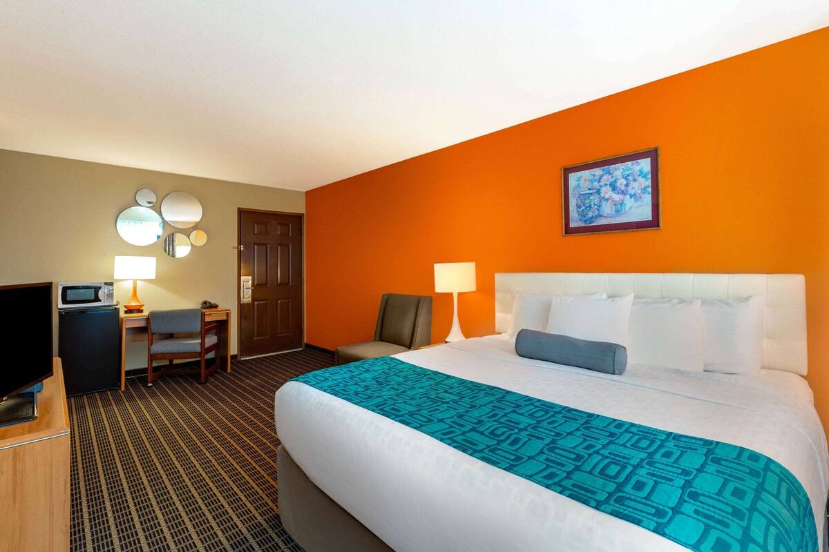 Una habitación de hotel con una cama grande, un escritorio con una computadora, una silla y un televisor.