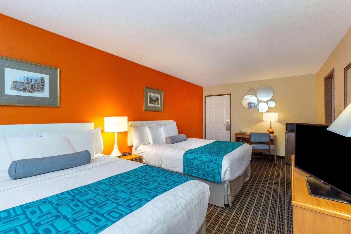 Una habitación de hotel con dos camas, televisión, escritorio y una silla.