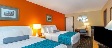 A hotel room with two beds, a television, a desk, and a chair.