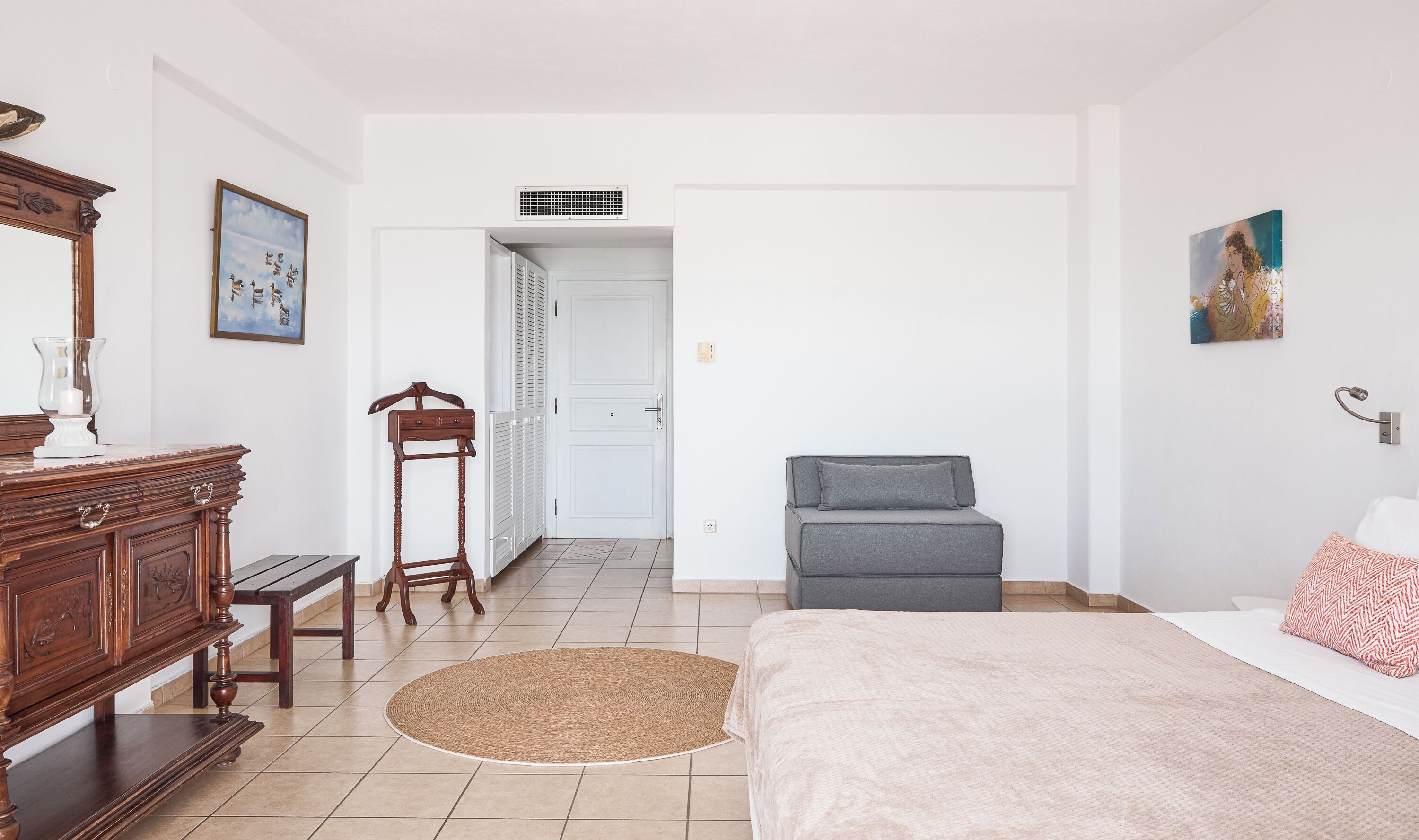 A bedroom with a bed, dresser, and a chair.