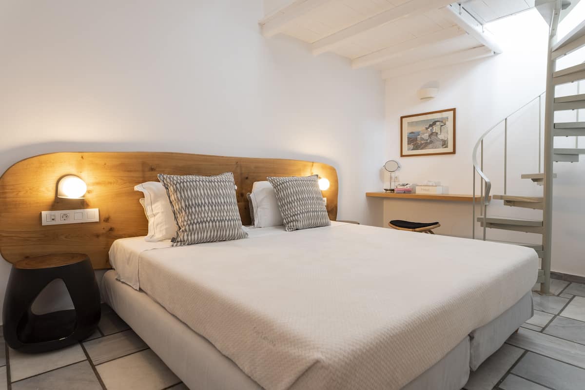A neatly made bed with a wooden headboard, bedside lamps, and a small bedside table with a lamp.