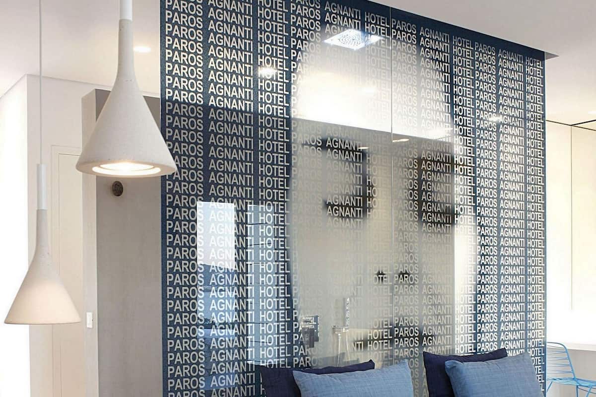 A modern bedroom with a large bed, a white bedside table, a blue patterned partition, and a hanging light fixture.