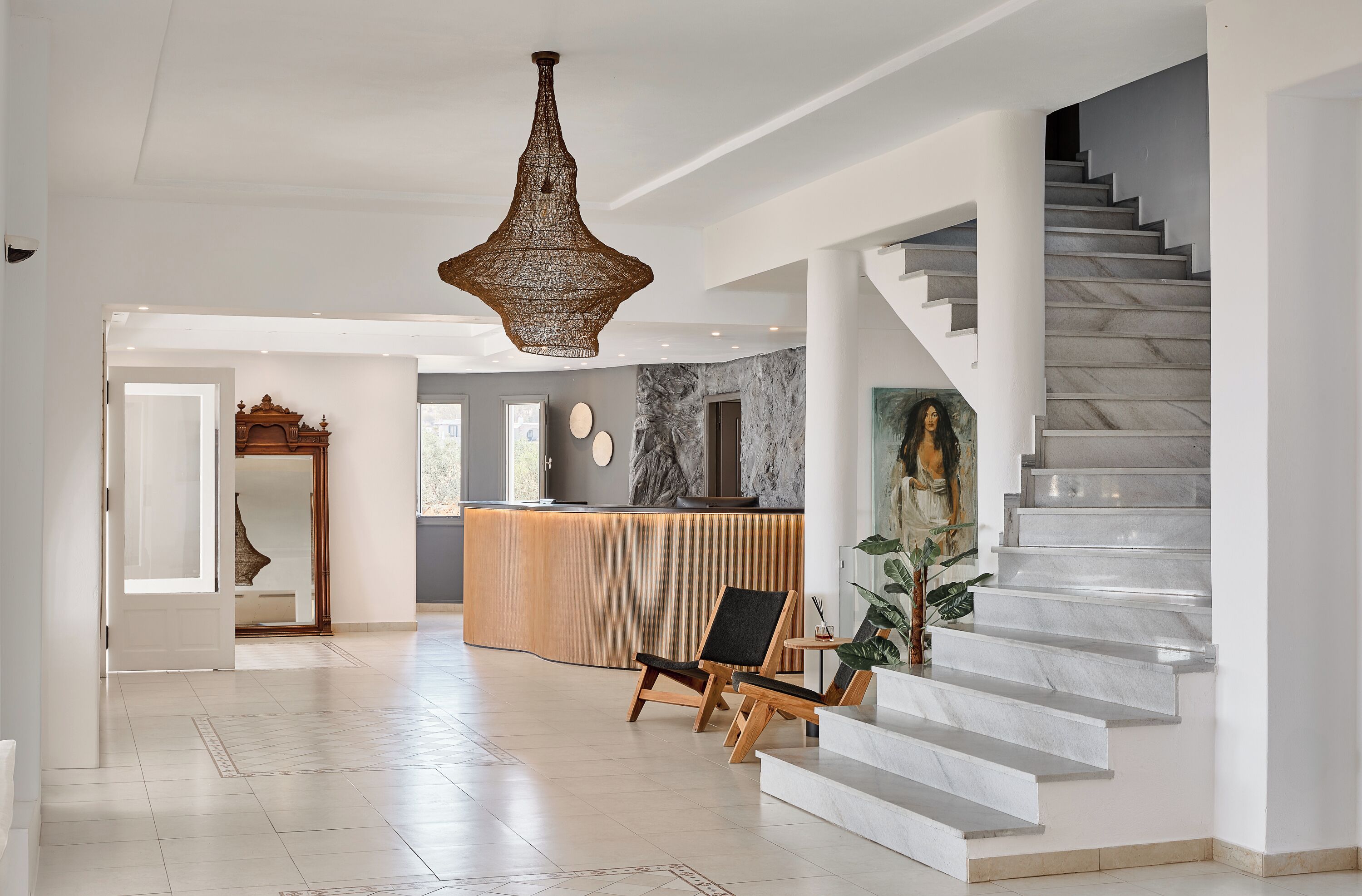 A spacious lobby with a reception desk, a staircase, and a large chandelier.