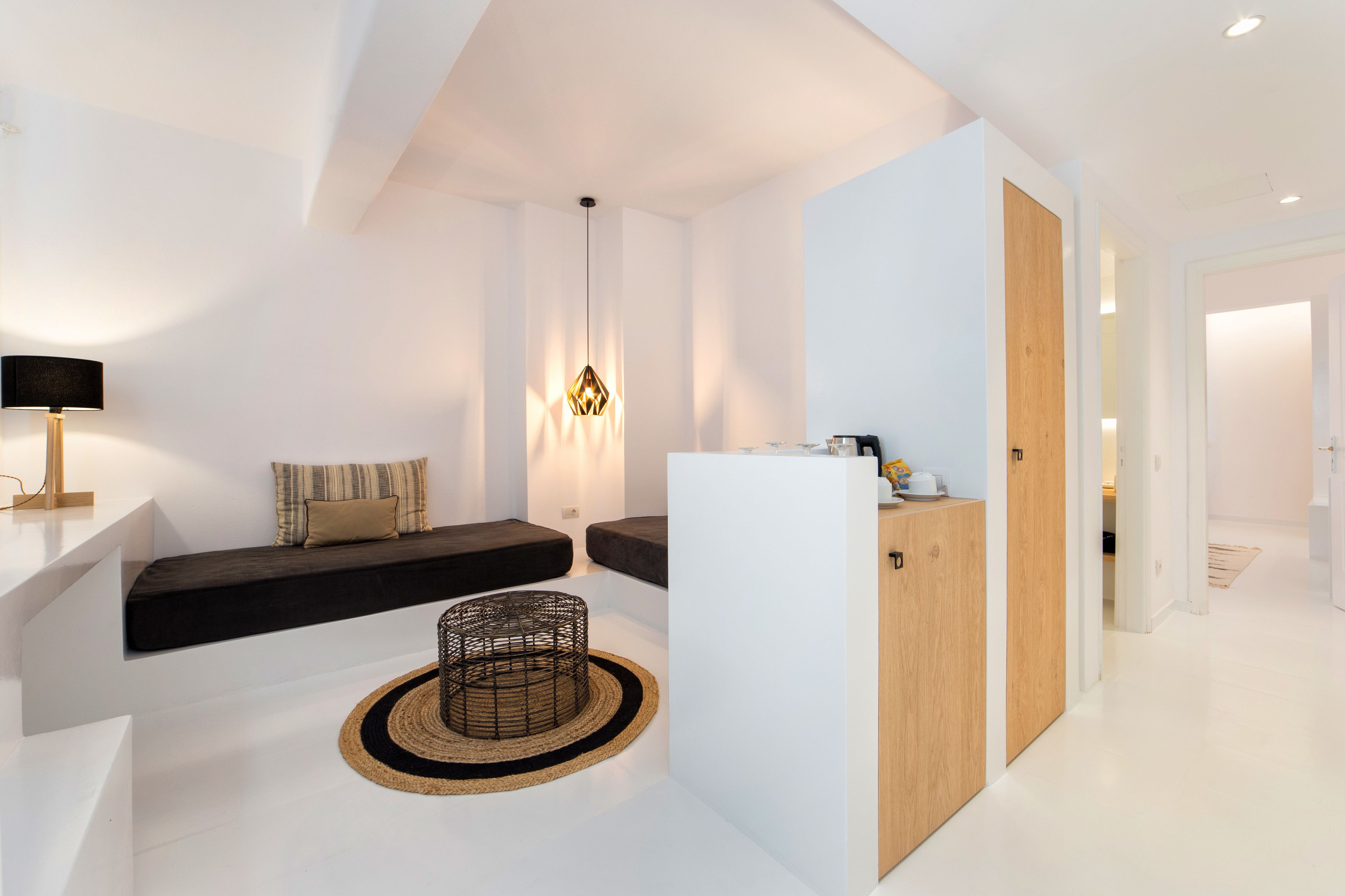 Un espacio habitable moderno y minimalista con un sofá, una mesita y una lámpara decorativa.