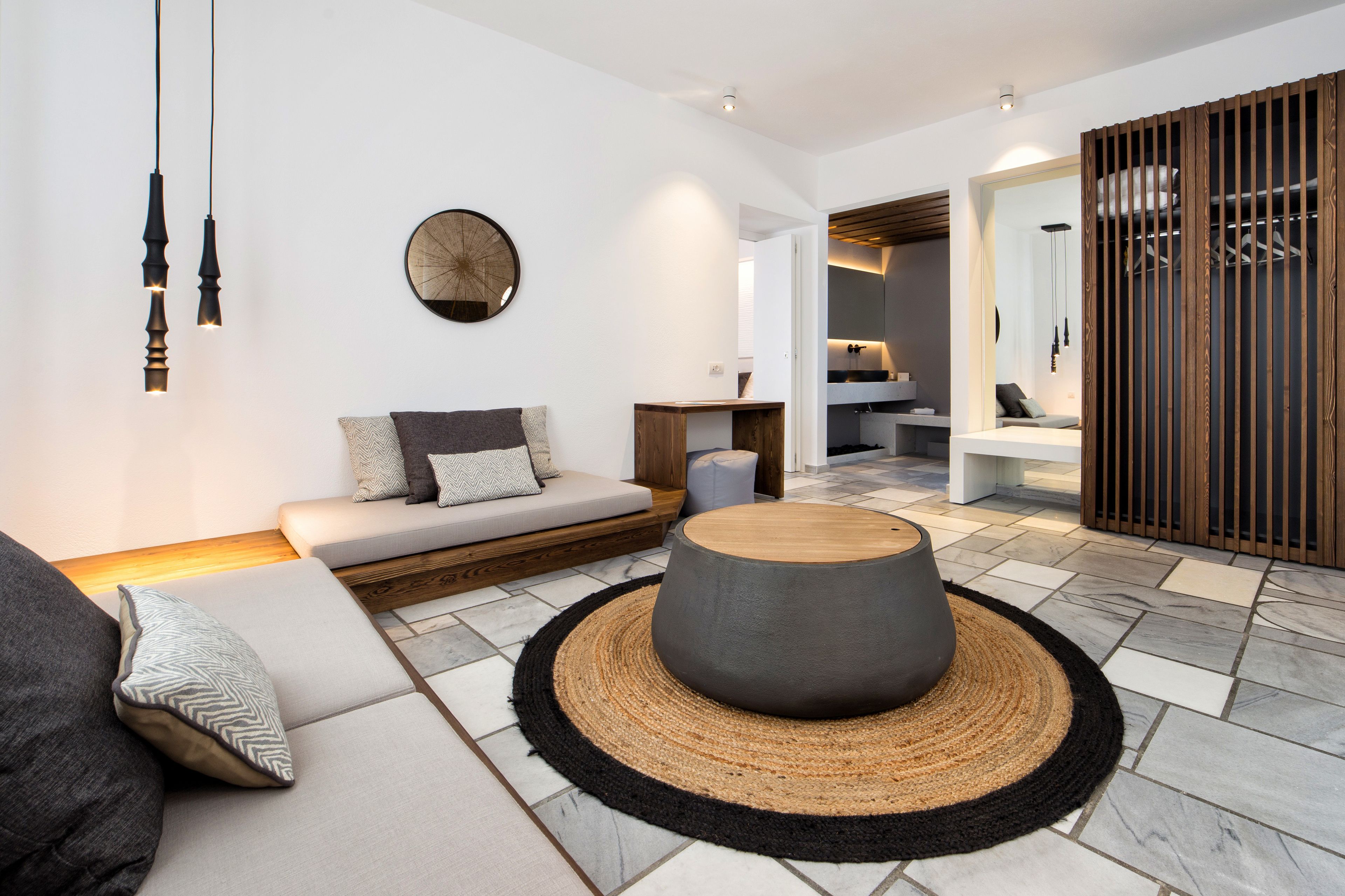 A modern living room with a sofa, a round coffee table, and a dining area with a wooden partition.