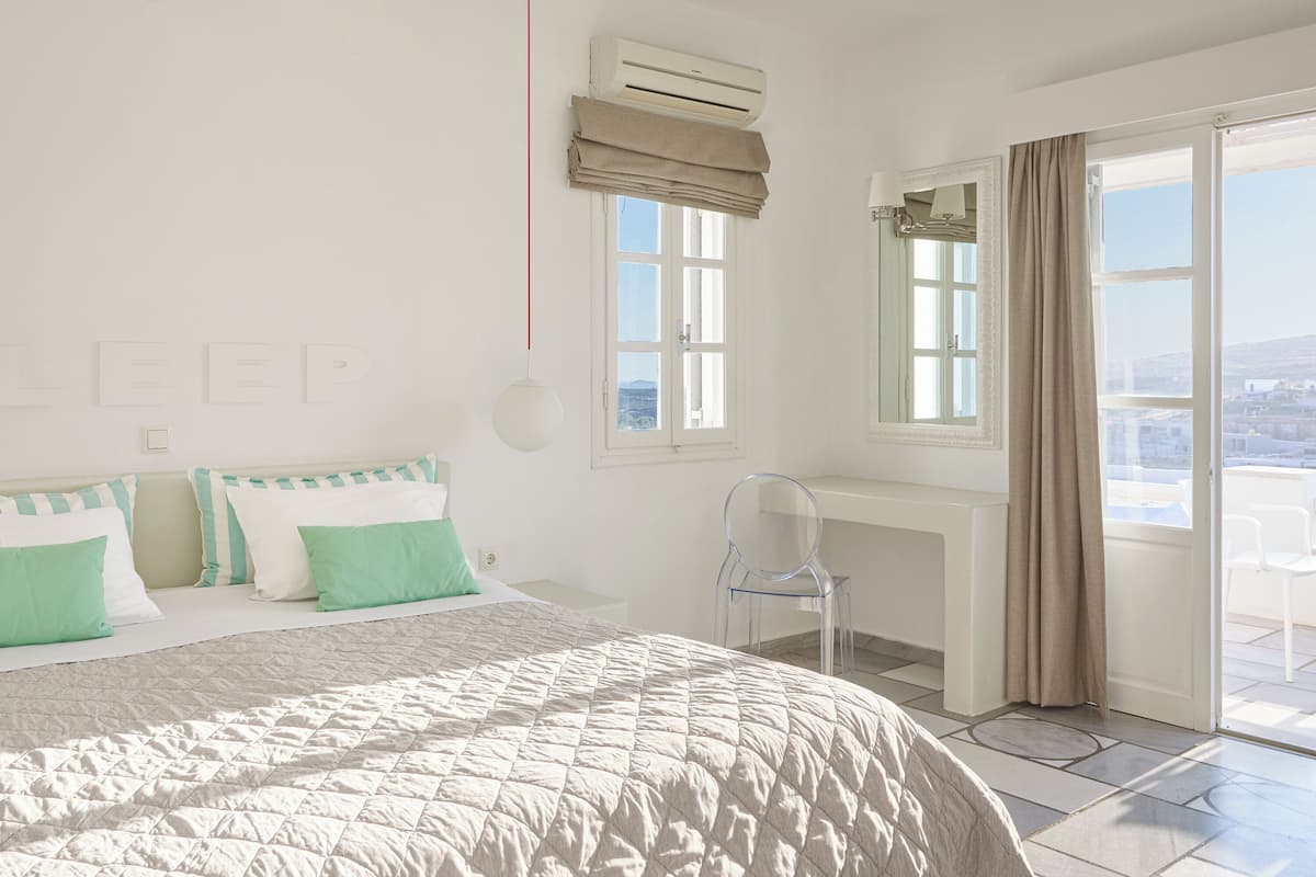 A bedroom with a bed, a desk, and a view of the city.